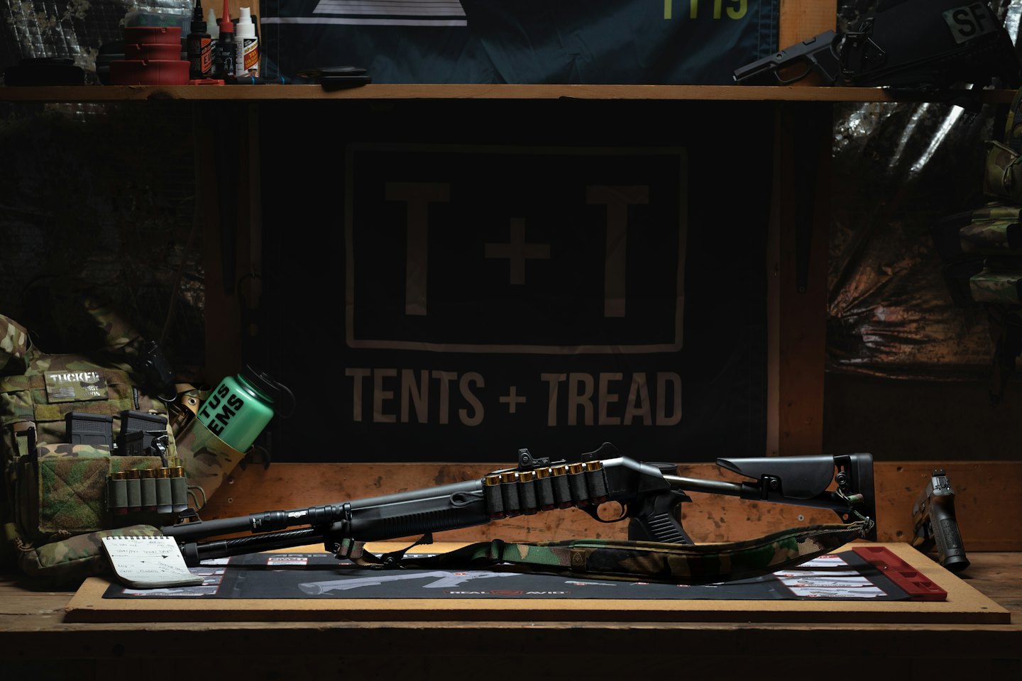 Taktyczny pistolet i strzelba leżące na drewnianym stole warsztatowym.